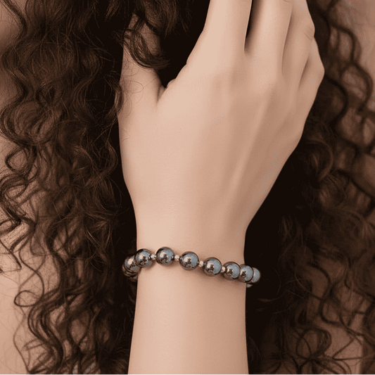 Bracelet en perles d’hématite porté au poignet, billes noir argenté brillantes